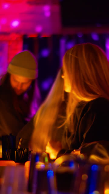 Vertical Shot of Two Women Ordering Drinks at a Bar During a Show
