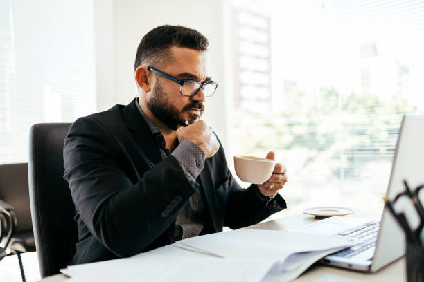 istock Businessman analyzing strategy on laptop while having coffee at office 1465643395