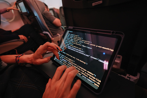 Female computer programmer doing work on a digital tablet during the flight.