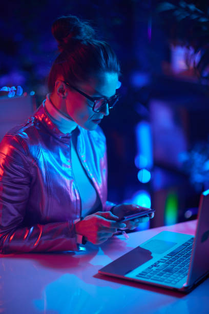 istock stylish woman in glasses with laptop using smartphone app 1465645719