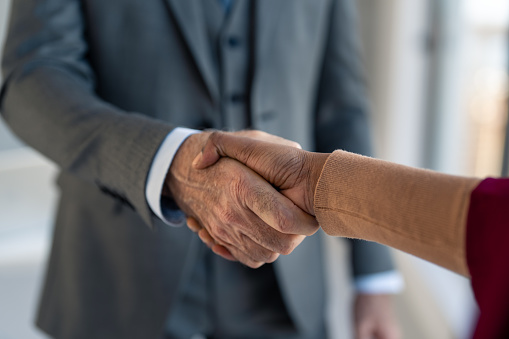 Diverse businesspeople, multiethnic coworkers shaking hands. Recruitment concept to hiring of a new talented specialists for international company. Senior executive greeting new female employee handshake.