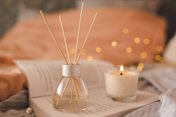 istock Home liquid diffuser with fragrance with candle and open book in bedroom close up 1465647420