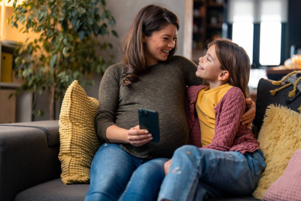 istock Mother and daughter using smart phone while resting at home 1465647870