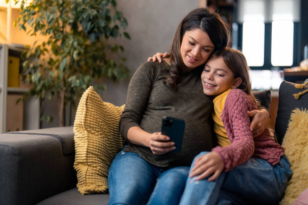 istock Caring woman looking at smartphone device screen with her young daughter 1465648044