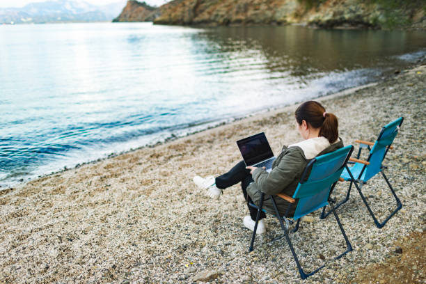 istock Adult woman working at the beach using laptop 1465648969