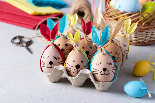 Easter bunnies made of eggs with multi-colored ears made of colored paper or napkins. Idea for decorating Easter eggs