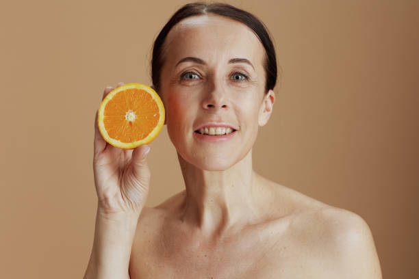istock happy modern woman with orange on beige background 1465649836