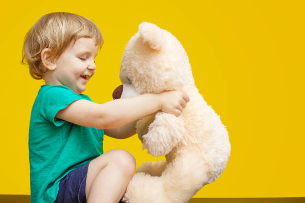 istock Little boy hugging teddy bear toy on yellow background 1465650759