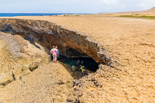 Aruba. Oranjestad. 02.12.2023. Beautiful view of tourists swimming in natural cave on Atlantic Ocean coastline.