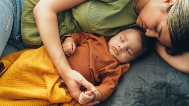 Young mother and baby napping at home stock photo