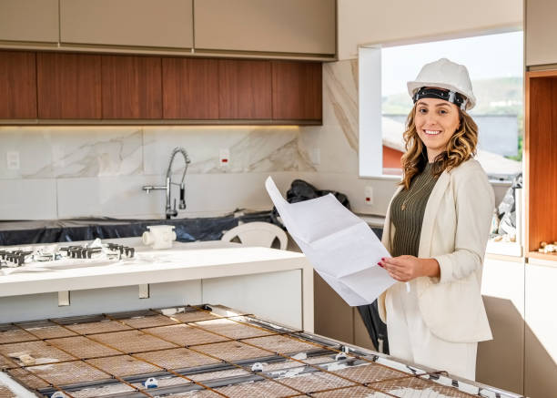 Confident female with a drawing standing in kitchen of a under construction site