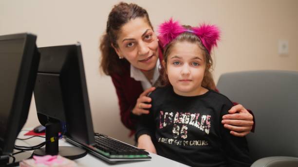 retrato de una niña pequeña con su maestra aprendiendo a leer y usar la computadora - computer lab child internet development fotografías e imágenes de stock