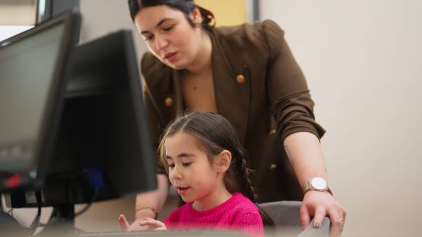 작은 소녀에게 컴퓨터를 읽고 사용하는 방법을 가르치는 교사 - computer lab child internet development 뉴스 사진 이미지