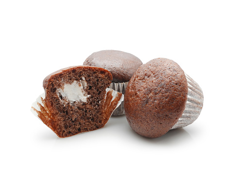 Two chocolate muffins and half with creamy filling isolated on white background