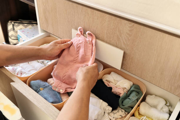 manos de mujer ordenando la ropa del bebé en los cajones. concepto - ropa de bebé fotografías e imágenes de stock