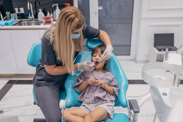istock Female dentist examining girl's teeth 1465665737