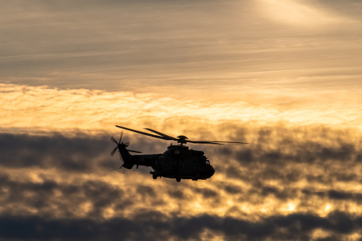 silhouette of a military helicopter against the setting sun