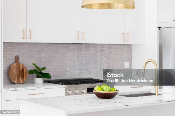 A White Kitchen Detail With Gold Light And Faucet Stock Photo - Download Image Now - Kitchen, Apartment, Cabinet