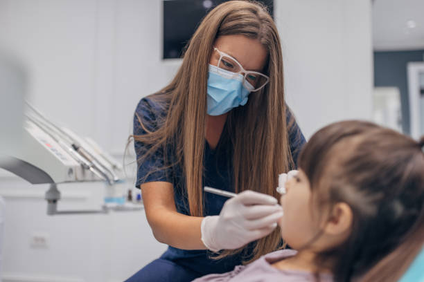 istock Female dentist examining girl's teeth 1465672903