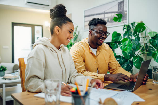 istock Diverse couple using laptop while sitting at the table at home 1465675367