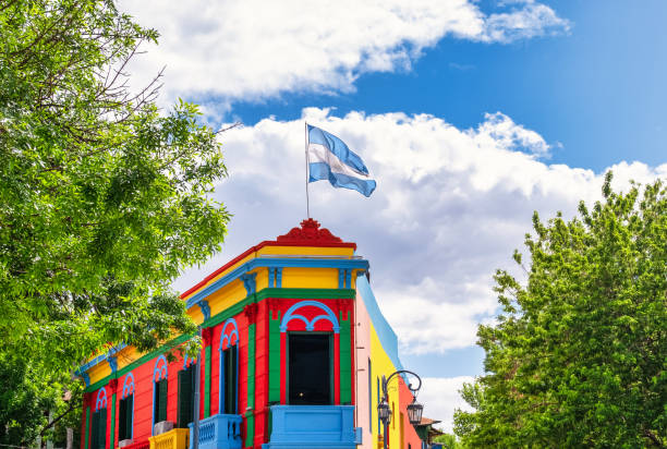 Caminito building in La Boca district, Buenos Aires, Argentina Typical brightly colored building on Caminito street in La Boca district, Buenos Aires, Argentina - Argentine flag on top of building with blue sky with clouds la boca stock pictures, royalty-free photos & images