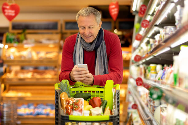 istock Smiling senior man using cell phone while shopping at supermarket 1465677955