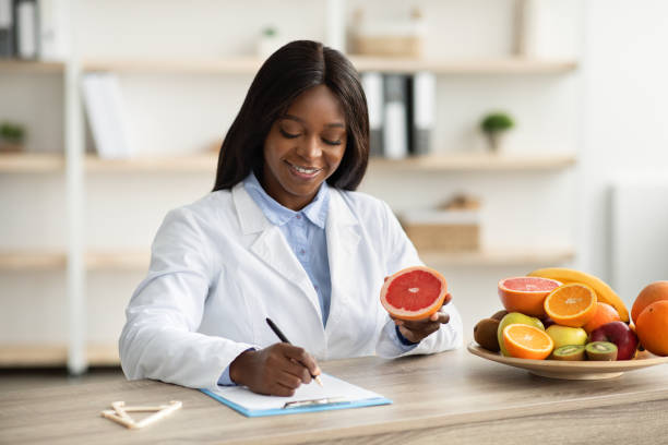 istock Happy black female nutrition adviser holding grapefruit, making meal plan for client at weight loss clinic 1465678273