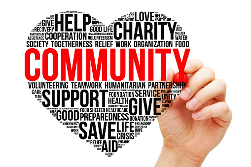 Hand writing Community word cloud in a heart shape. Concept about charity, humanitarian relief aid work, or empathy.