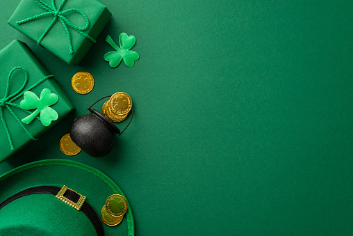 Saint Patrick's Day concept. Top view photo of leprechaun hat gift boxes pot with gold coins and clovers on isolated green background with copyspace