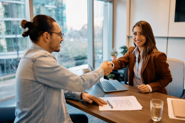 Happy businesswoman shaking hands with job candidate in the office. Happy human resource manager greeting candidate during job interview in the office. job interview stock pictures, royalty-free photos & images