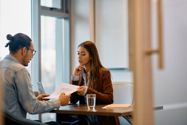 Human resource manager going through documents with male candidate in the office. Young businesswoman and her male coworker analyzing reports while working in the office. Copy space. job interview stock pictures, royalty-free photos & images