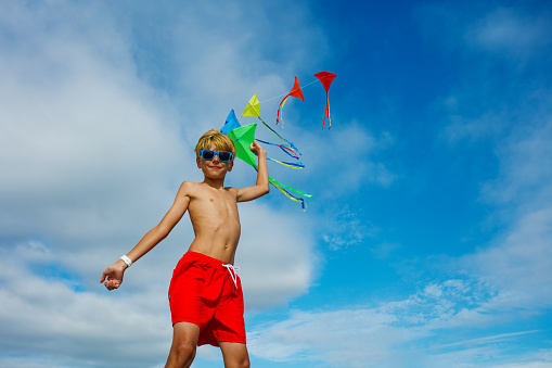 Llittle boy flies a kite into the blue sky
