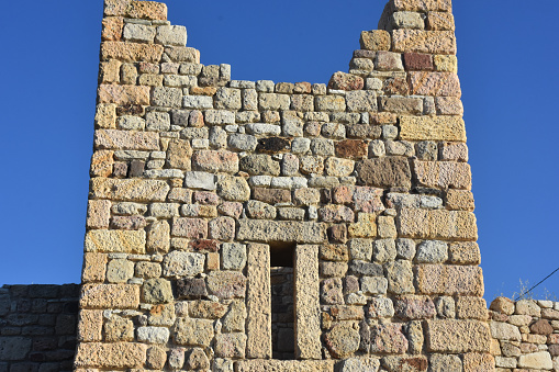 Detailed stone walls of a ruined old medieval castle and a clear sky behind it