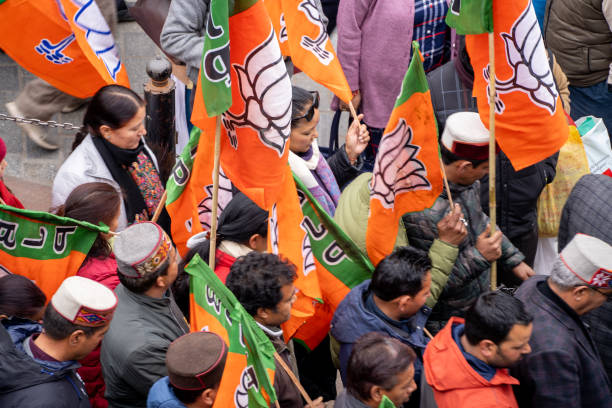 aerial drone shot crowd people with saffron flags of BJP protesting or celebrating victory in hill station manali standing in circle with leader stock photo