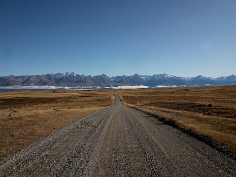 Backcountry dirt gravel road Braemar Road leading to Lake Pukaki, Southern Alps mountain nature landscape panorama in Mackenzie County Canterbury South Island New Zealand