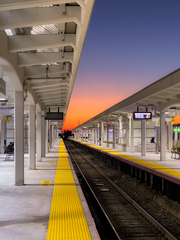 Hicksville, New York - October 14, 2022 : The Hicksville Long Island Railroad (LIRR) train platform just after sunset with a colorful glowing sky