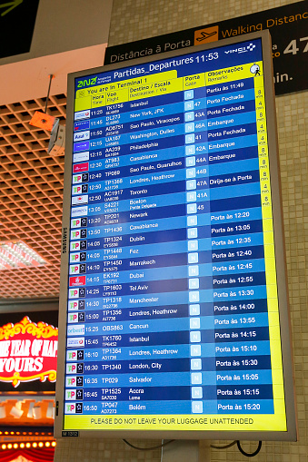 Lisbon, Portugal- May 26, 2019: Information panel for departures and arrivals next to a clock at the airport of Lisbon