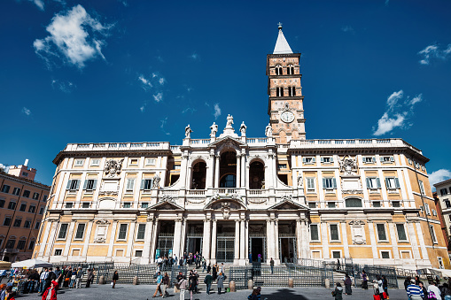 People stand in front of Basilica di Santa Maria Maggiore in downtown Rome, Italy on a sunny day. Basilica di Santa Maria Maggiore is one of the four papal basilicas.