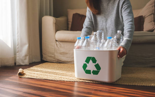 istock Closeup image of a woman collecting and separating recyclable garbage plastic bottles into a trash bin at home 1465719081