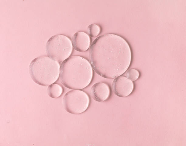 Cosmetic lotion transparent gel drops texture background, pink stock photo