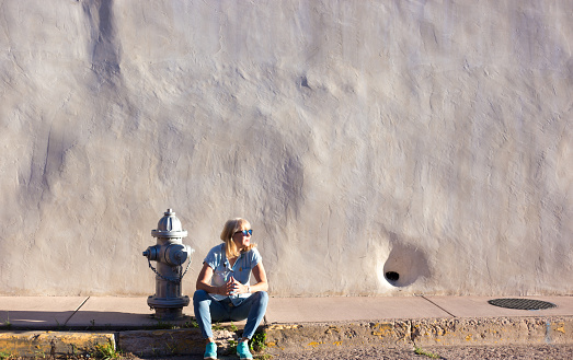 Woman Walks by Sunlit Adobe Wall, Fire Hydrant, Southwest USA