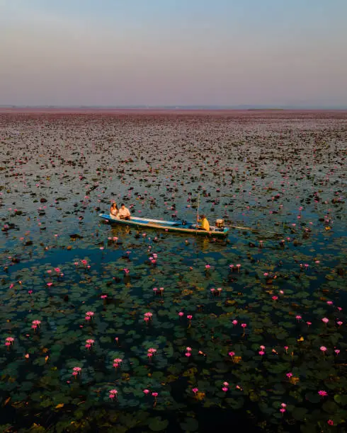 Photo of Men and women in a boat at Sunrise at The sea of red lotus, Lake Nong Harn, Udon Thani, Thailand
