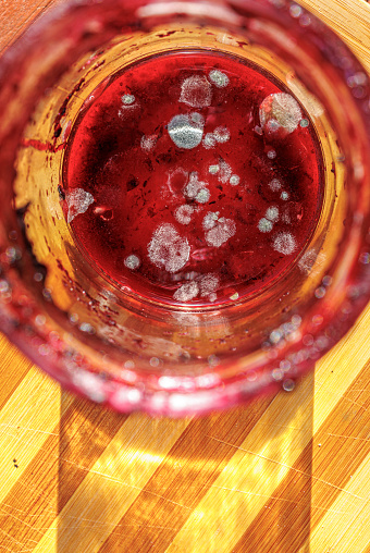 A jar with spoiled jam with mold on a cutting board.