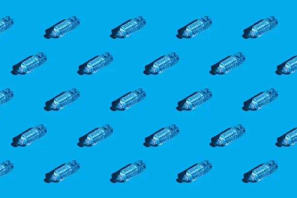 Overhead view of plastic water bottles in rows on a bright blue background