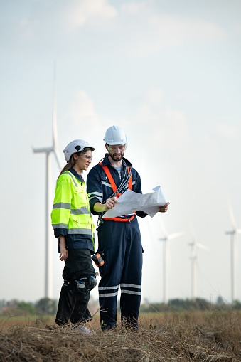 Man and female engineer stationed at the Natural Energy Wind Turbine site. with daily audit tasks of major wind turbine operations that transform wind energy into electrical electricity