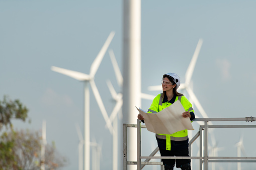 Portrait of female engineer at Natural Energy Wind Turbine site with the mission of being responsible for taking care of large wind turbines