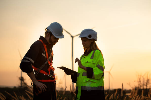 istock Engineers working on wind farms for renewable energy are responsible for maintaining large wind turbines. Review all tasks of the day while the evening sun shines a beautiful golden light upon both of them 1465739564