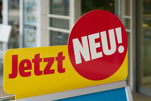 Sign with the German inscription jetzt neu as advertising in front of a store in downtown Magdeburg. Translation: now new