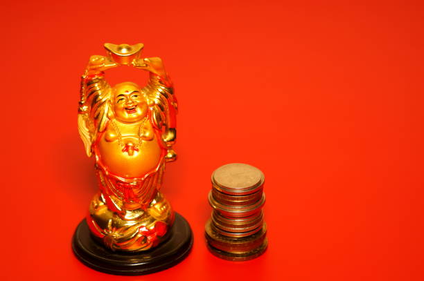 istock Buddha statuette with coins on a red background. 1465753377