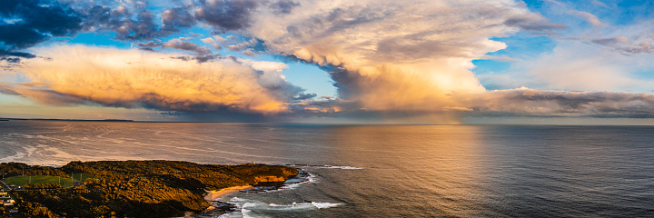 Panorama of dramatic storm cell with rain at sunset over the open ocean. Photographed on the east coast of Australia.